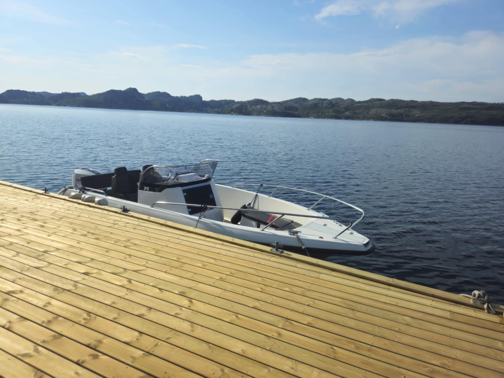 Nytt tredekk ved sjøen med båt fortøyd